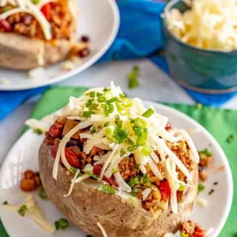 Loaded chili stuffed baked potatoes are the perfect way to use up leftover chili! Tender, fluffy potatoes are filled with warm chili and topped with all your favorite toppings. #chili #potatoes #bakedpotatoes #stuffedpotatoes #easydinner
