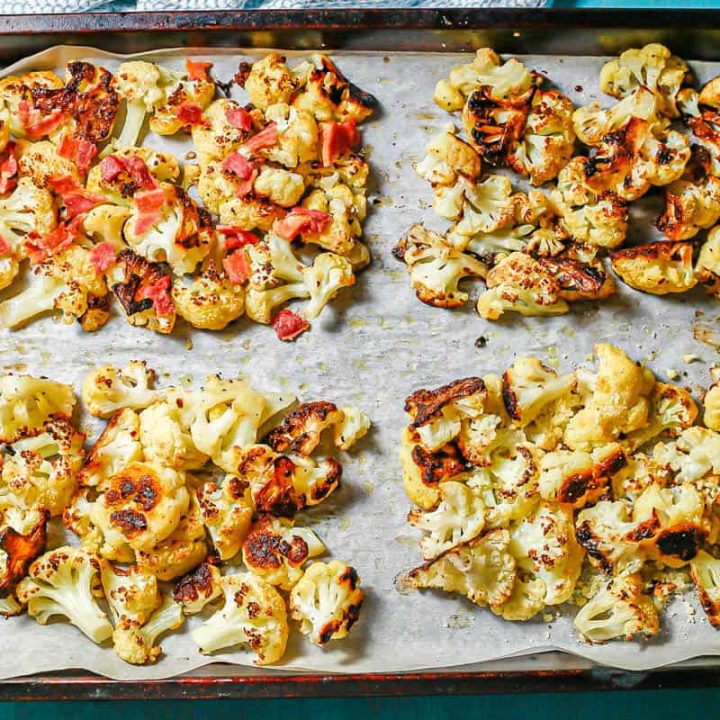 A parchment paper lined baking sheet with four separate quadrants of roasted cauliflower with different seasonings and toppings.